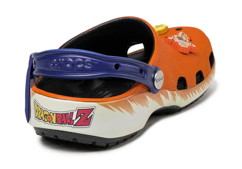 A rear view of the "Blerd Kicks: Dragon Ball Z x Crocs Classic Clog," showcasing the back strap with bold electric blue accents and Goku-inspired detailing. The strap features a subtle Dragon Ball Z logo for an extra touch of fandom pride, blending seamlessly with the orange clog base. The rear design highlights both comfort and style, perfect for casual wear or anime conventions.